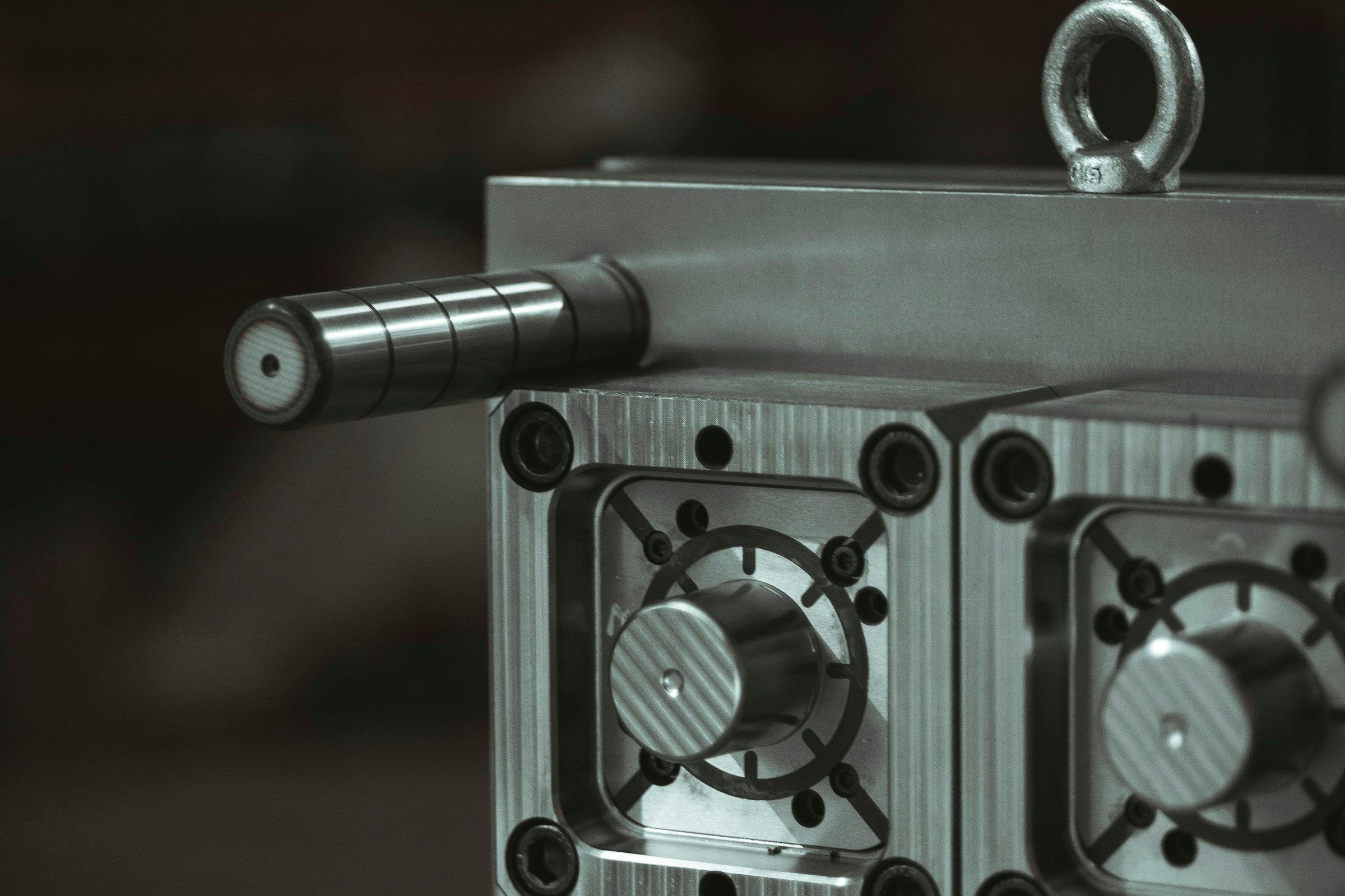 A multi-cavity injection mould half with a lifting eye bolt and guide pillar, rigged for moving